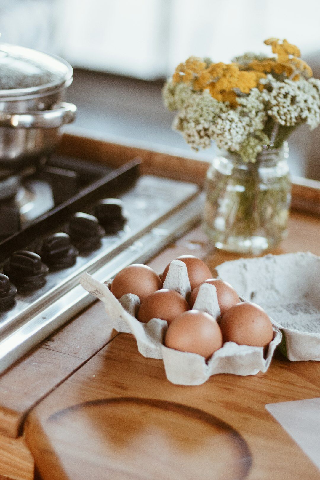 Fresh spring vegetables and herbs on a kitchen counter with Easter baking in background